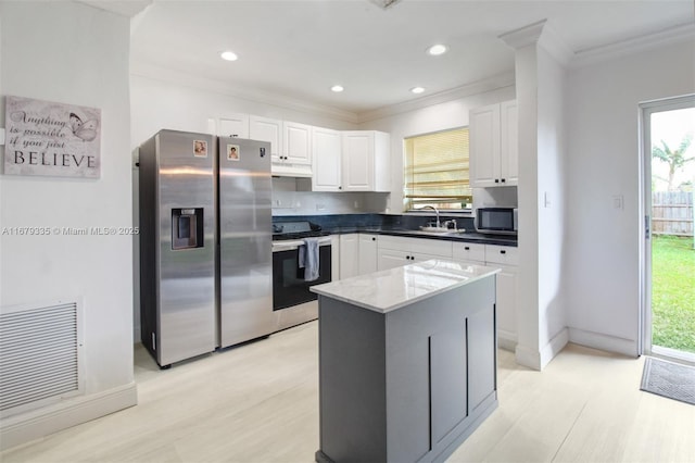 kitchen with stainless steel refrigerator with ice dispenser, a wealth of natural light, a kitchen island, range, and white cabinetry