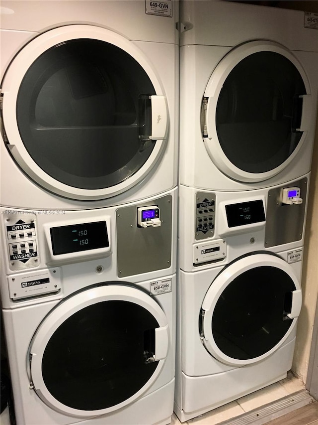 clothes washing area with stacked washing maching and dryer and light wood-type flooring