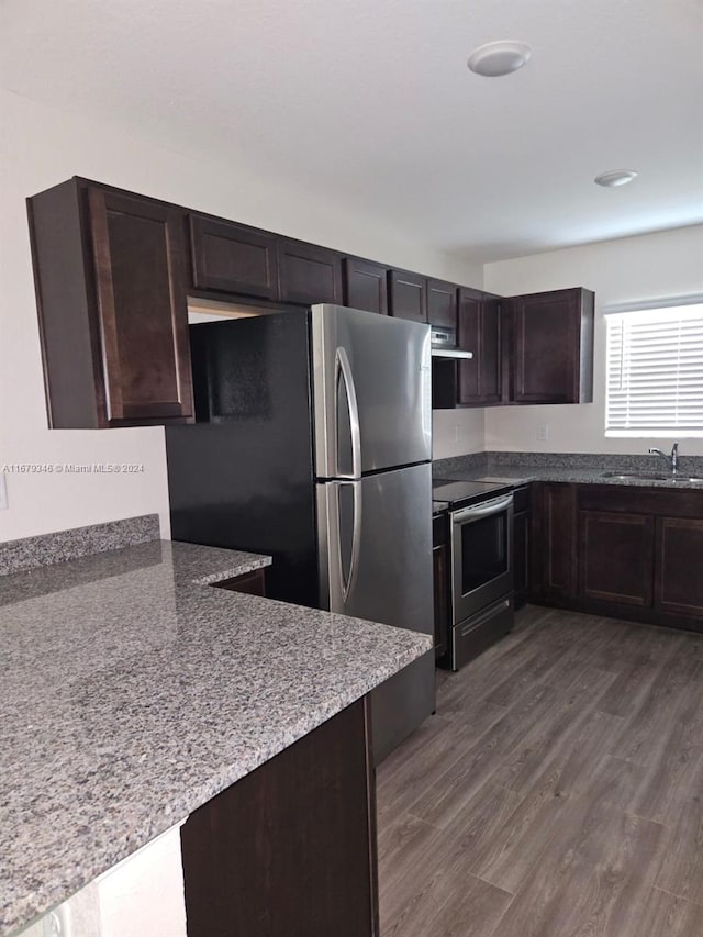 kitchen with exhaust hood, dark wood-type flooring, sink, dark brown cabinetry, and appliances with stainless steel finishes