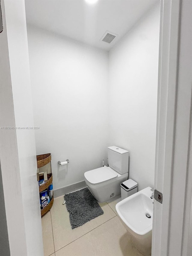 bathroom with toilet, a bidet, and tile patterned flooring