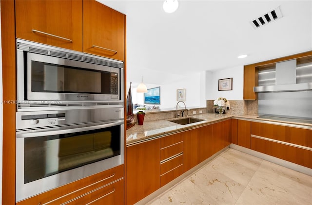 kitchen featuring light stone countertops, sink, appliances with stainless steel finishes, and wall chimney exhaust hood