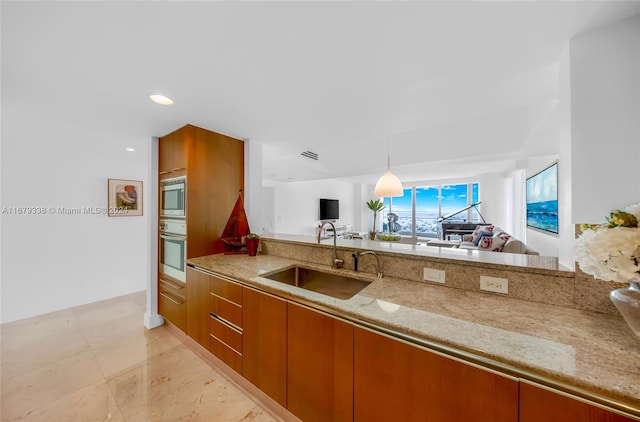 kitchen with stainless steel appliances, light stone countertops, sink, and decorative light fixtures