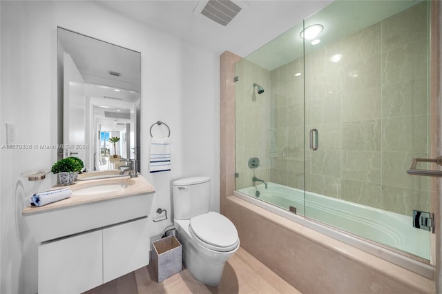 full bathroom featuring vanity, bath / shower combo with glass door, and toilet