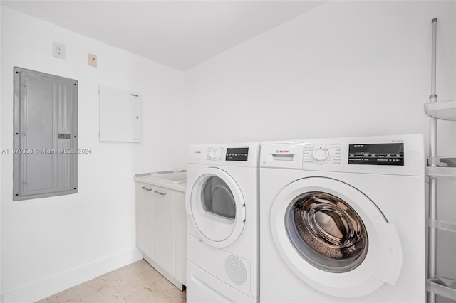 washroom featuring cabinets, electric panel, and washer and clothes dryer