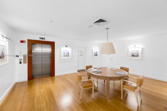 dining area featuring light hardwood / wood-style floors, a barn door, and elevator