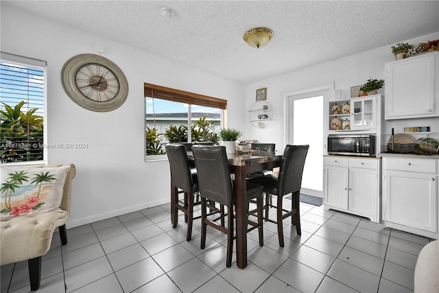 tiled dining space featuring a textured ceiling