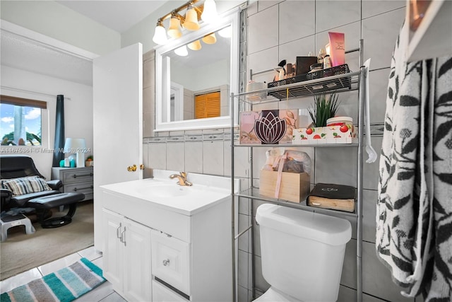 bathroom with toilet, decorative backsplash, vanity, and tile walls