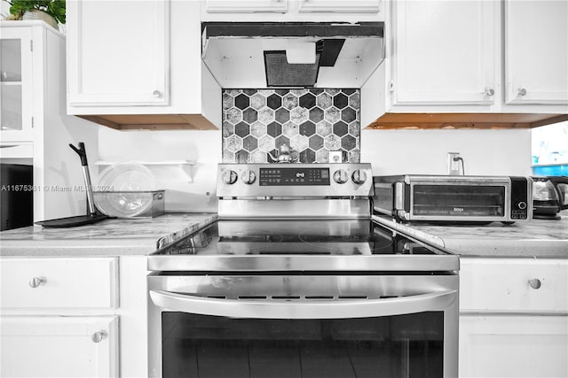 kitchen featuring white cabinetry, light stone countertops, decorative backsplash, and electric range