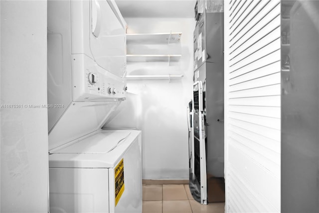 laundry area with stacked washer / dryer and light tile patterned floors