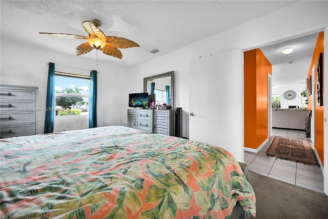 tiled bedroom with ceiling fan and a textured ceiling