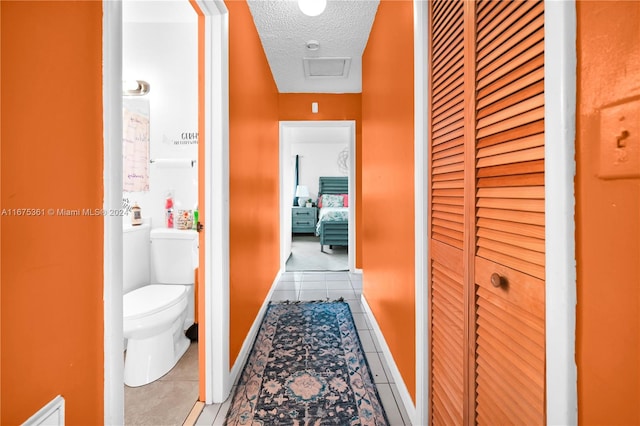 corridor featuring a textured ceiling and light tile patterned floors