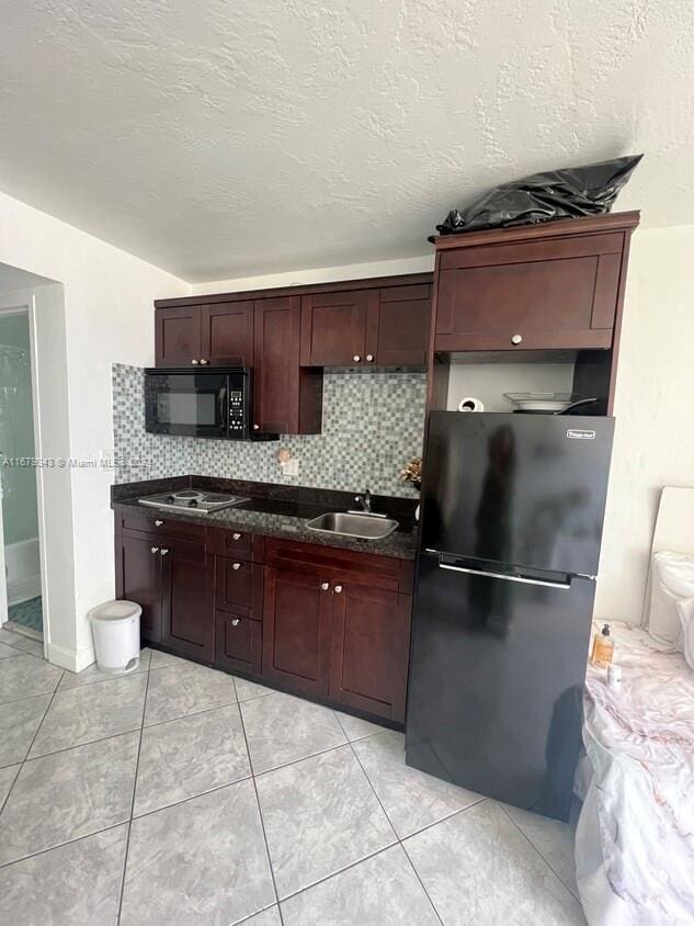 kitchen with sink, fridge, a textured ceiling, stainless steel stovetop, and decorative backsplash