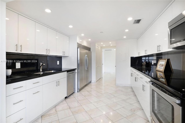 kitchen with stainless steel appliances, decorative backsplash, sink, and white cabinets