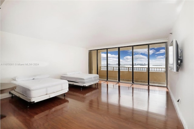 bedroom featuring wood-type flooring, a wall of windows, and access to exterior