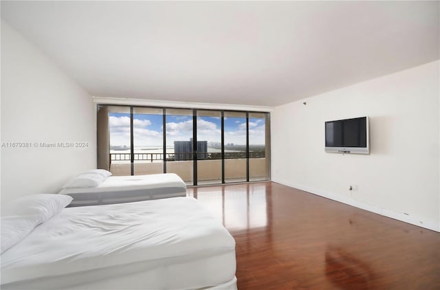 bedroom with access to outside, wood-type flooring, and a wall of windows