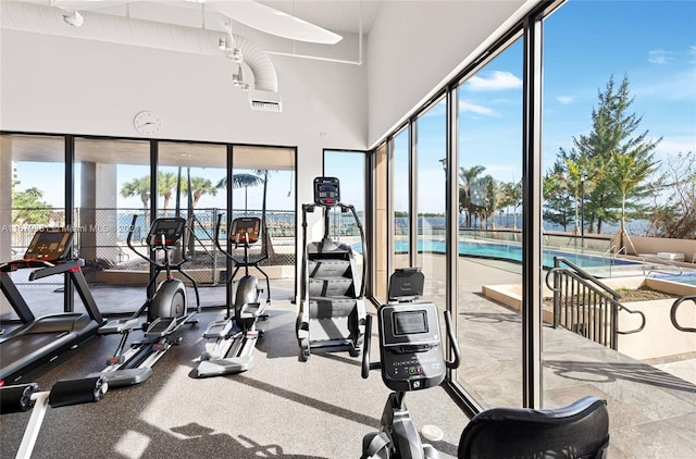 gym featuring a towering ceiling and plenty of natural light