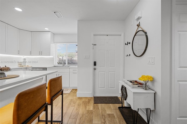 kitchen with light hardwood / wood-style floors, white cabinetry, and sink