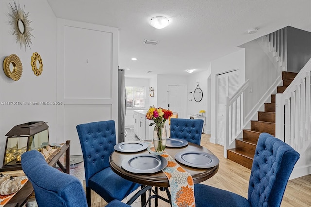 dining area with sink, a textured ceiling, and light hardwood / wood-style flooring