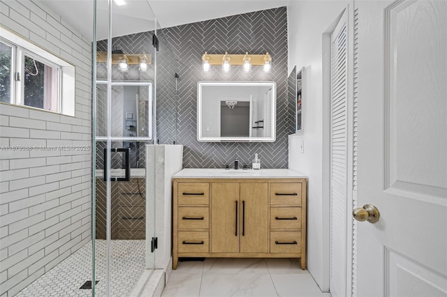 bathroom with vanity, backsplash, a shower with shower door, and tile walls