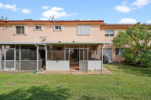 back of property with a sunroom and a lawn