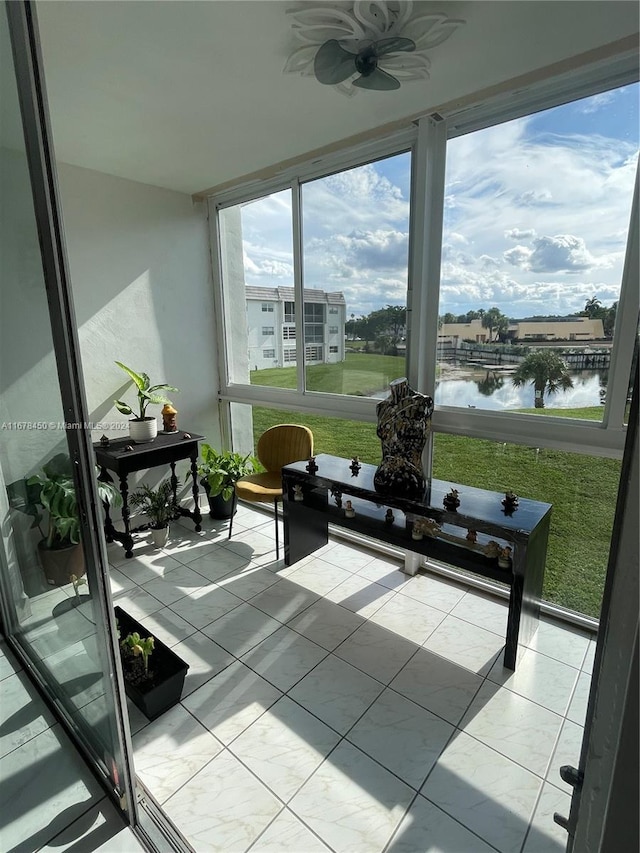 sunroom featuring a water view and ceiling fan