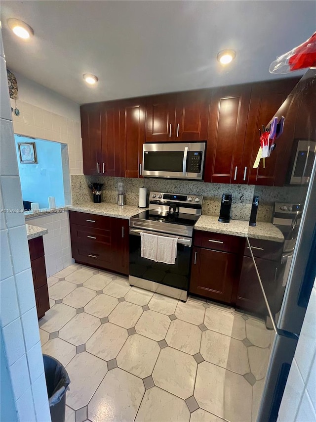 kitchen with light stone counters, appliances with stainless steel finishes, and decorative backsplash