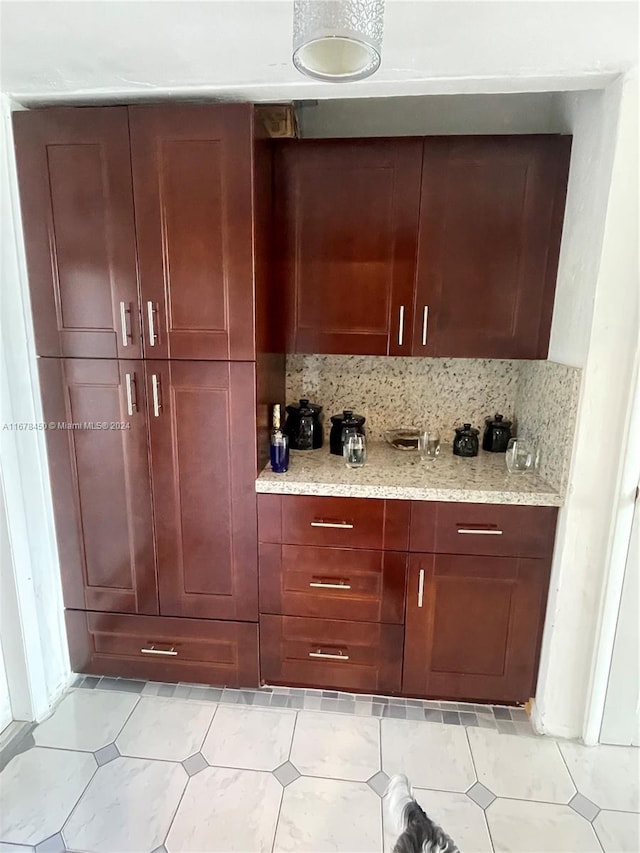 bar featuring decorative backsplash, light stone counters, and light tile patterned floors