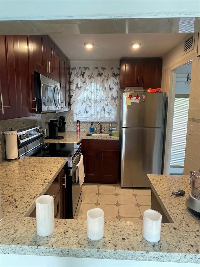 kitchen featuring backsplash, stainless steel appliances, light stone countertops, and sink