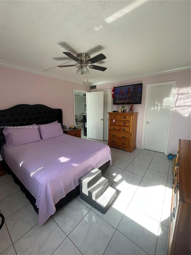 tiled bedroom with ceiling fan, a textured ceiling, and ornamental molding