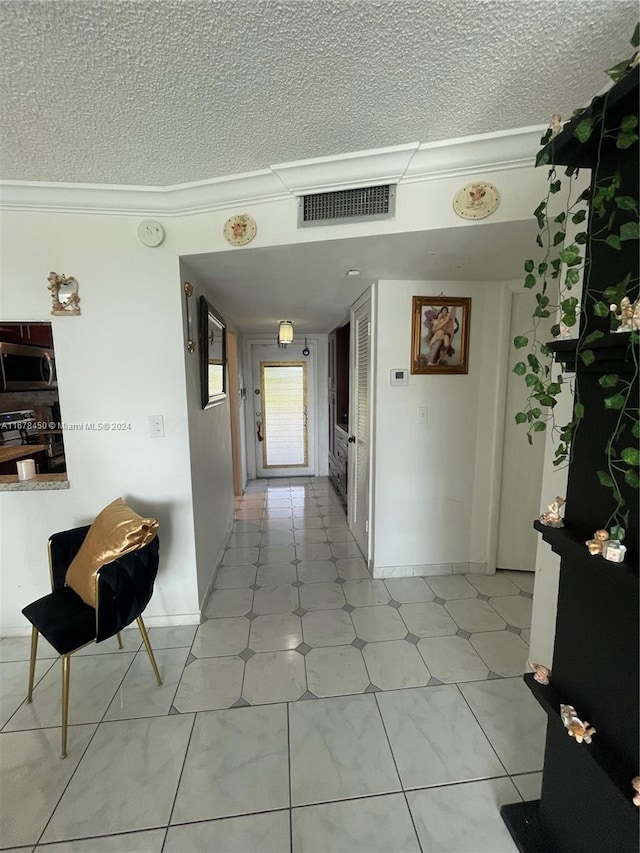 hall with light tile patterned flooring, ornamental molding, and a textured ceiling