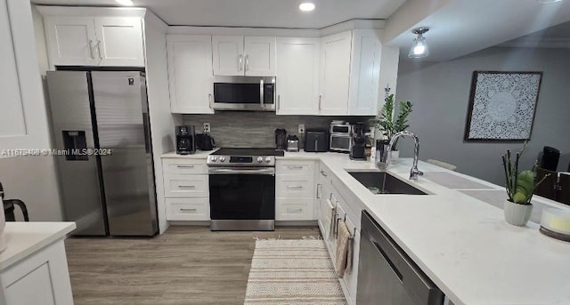 kitchen with appliances with stainless steel finishes, backsplash, sink, white cabinets, and light hardwood / wood-style floors