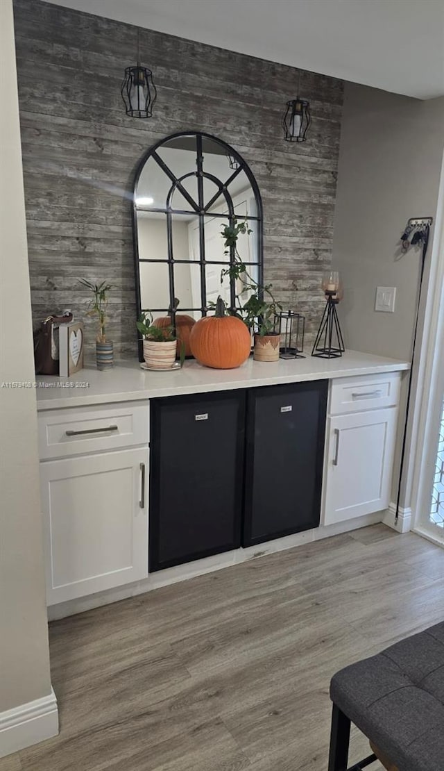 bar with white cabinets and light hardwood / wood-style floors