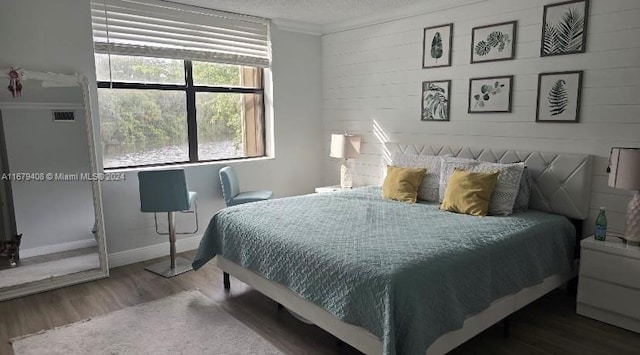 bedroom with wood-type flooring, a textured ceiling, and ornamental molding