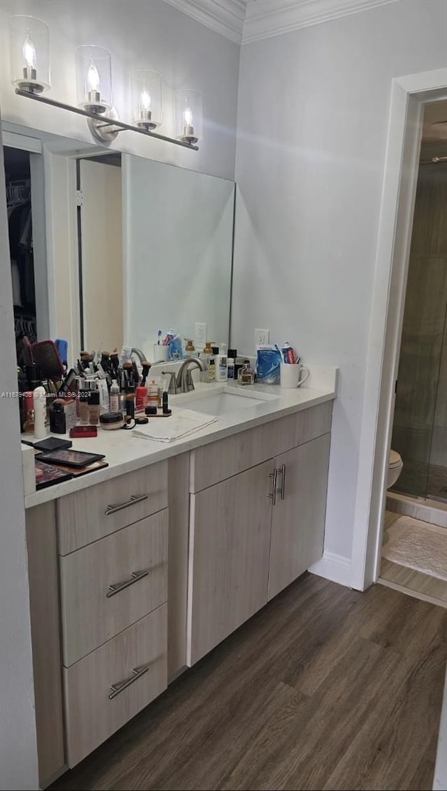 bathroom featuring an enclosed shower, ornamental molding, vanity, hardwood / wood-style flooring, and toilet