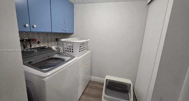 laundry room with hardwood / wood-style flooring, cabinets, separate washer and dryer, and a textured ceiling