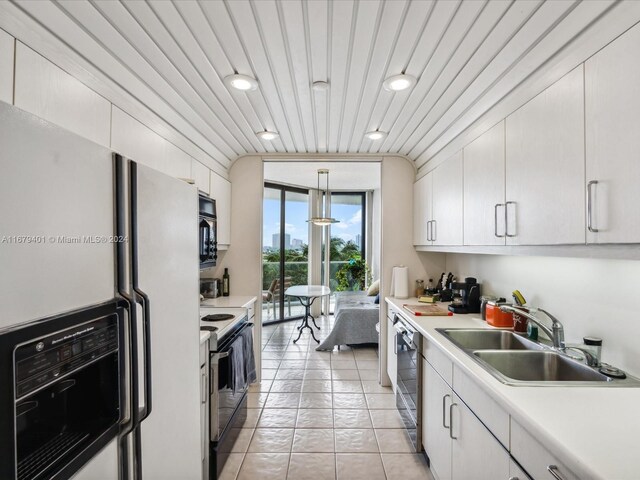 kitchen featuring light tile patterned floors, white cabinetry, black appliances, sink, and decorative light fixtures