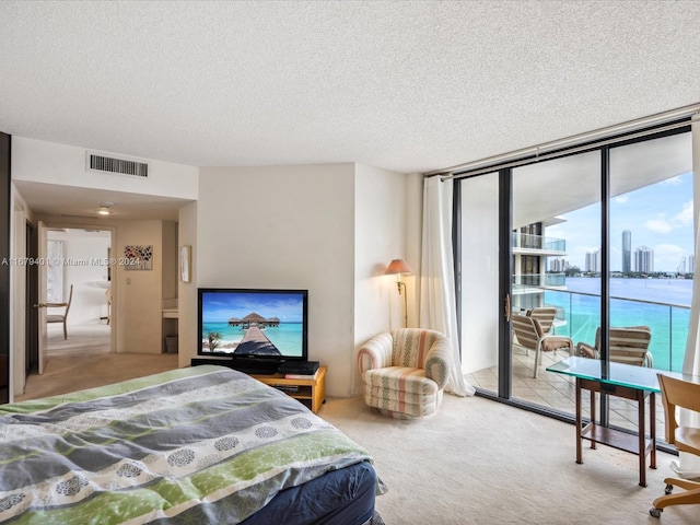 carpeted bedroom featuring a textured ceiling, a wall of windows, and access to exterior