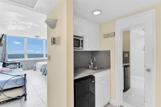 kitchen featuring dishwasher, sink, backsplash, white cabinets, and a water view