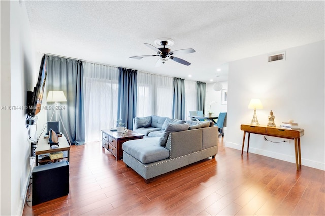 living room featuring a textured ceiling, wood-type flooring, and ceiling fan