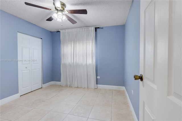 spare room featuring ceiling fan, a textured ceiling, and light tile patterned floors