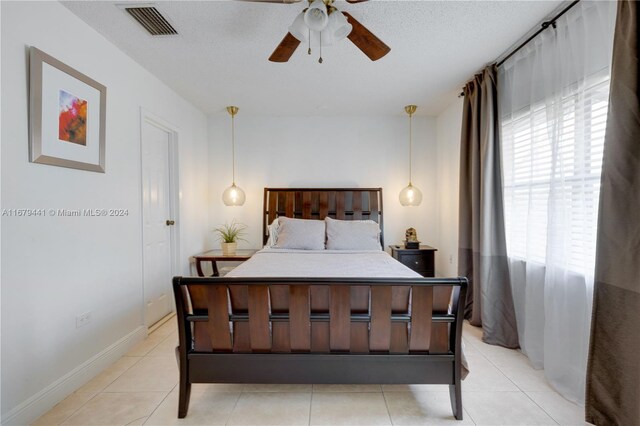 bedroom featuring a textured ceiling, light tile patterned flooring, multiple windows, and ceiling fan