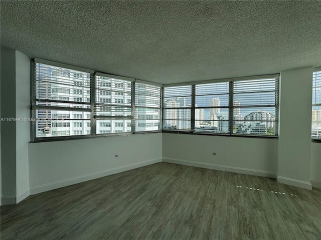 spare room with a textured ceiling and dark hardwood / wood-style flooring