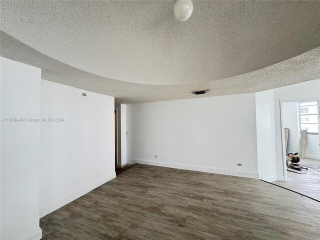 spare room with a textured ceiling and dark hardwood / wood-style floors