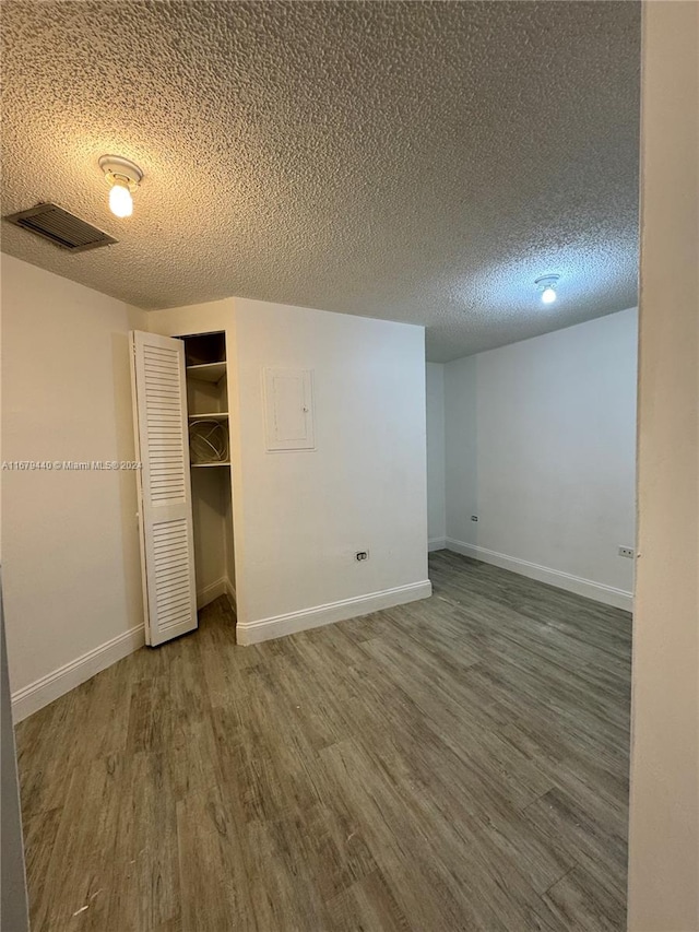 unfurnished bedroom with a closet, a textured ceiling, and dark hardwood / wood-style floors