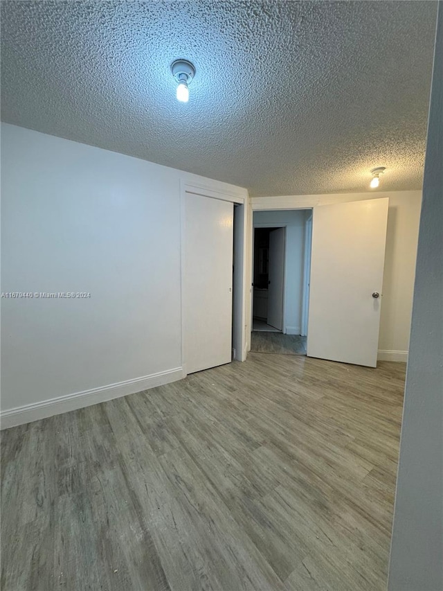 unfurnished room with a textured ceiling and light hardwood / wood-style flooring