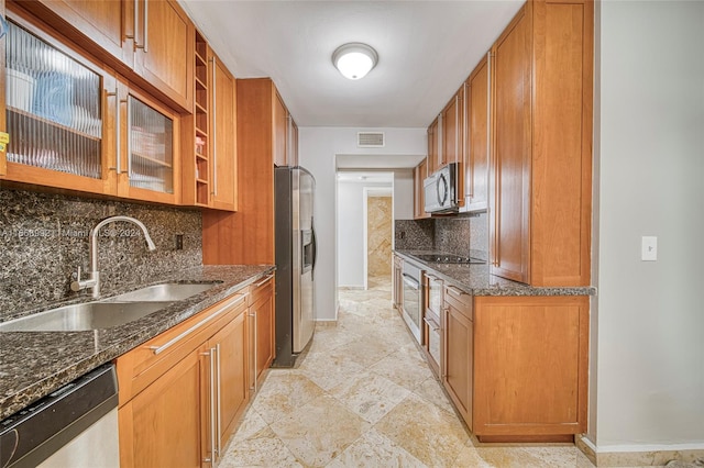 kitchen with sink, backsplash, appliances with stainless steel finishes, and dark stone counters