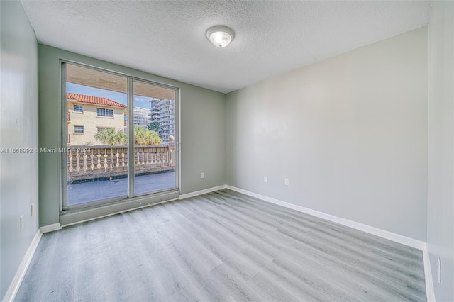 empty room with light hardwood / wood-style flooring and a textured ceiling