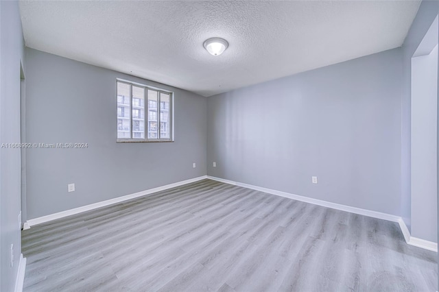 spare room with a textured ceiling and light wood-type flooring