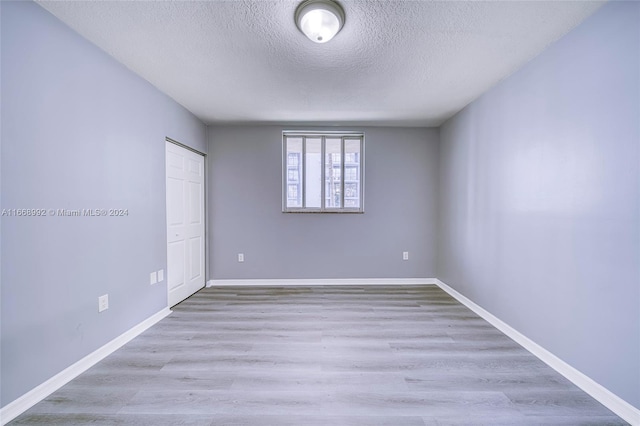 empty room with light hardwood / wood-style flooring and a textured ceiling