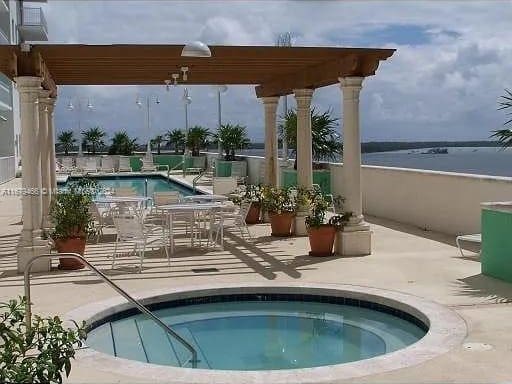 view of pool with a water view, a hot tub, and a patio